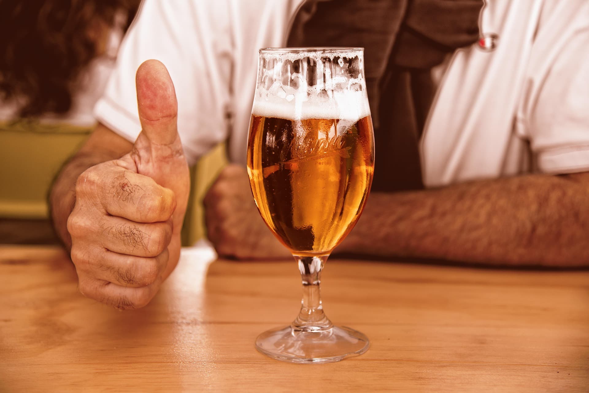 Un demi de bière et un homme qui montre son pouce